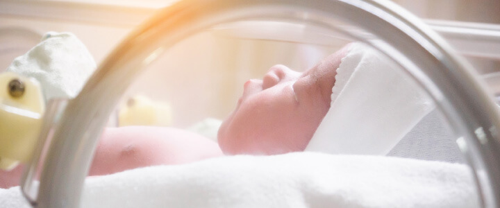 Newborn baby inside incubator in hospital post delivery room
